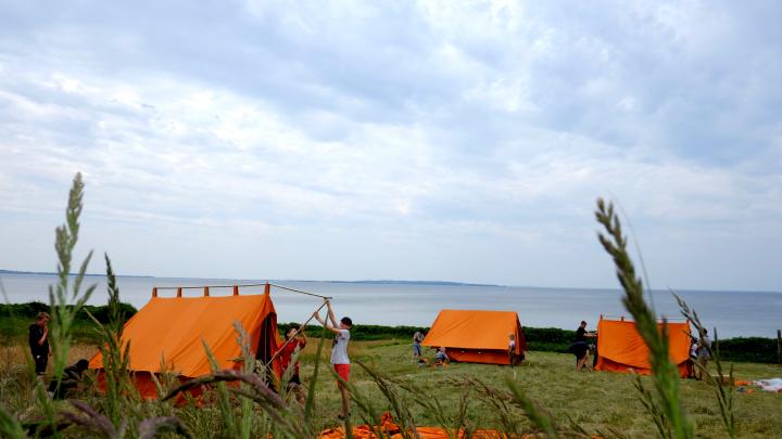 Billede af nogle spejderdrenge der er ved at få samlet et telt ved stranden
