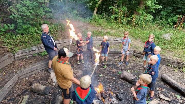 Glade spejderdrenge samles omkring bålet